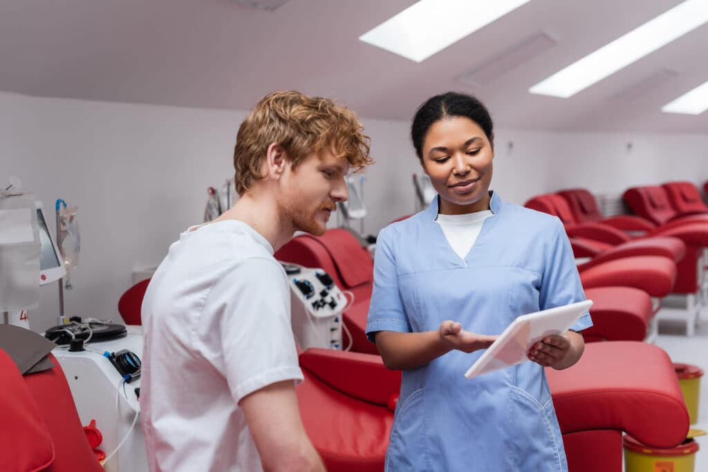 NE-BC Certification Exam Preparation Nursing leadership professional using a digital tablet to educate a patient and support informed clinical care decisions in a modern healthcare setting
