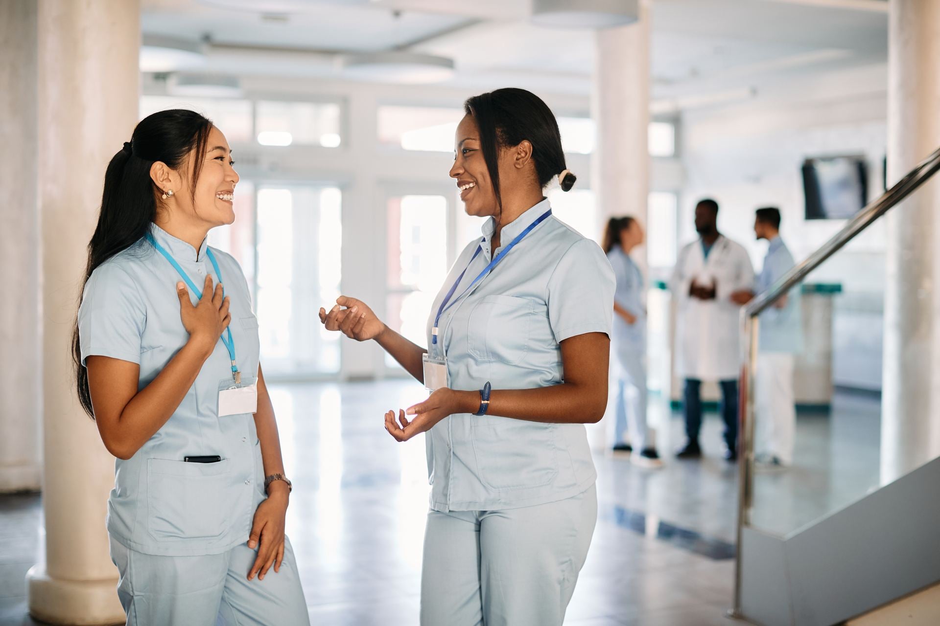 NPD-BC Exam Eligibility & Requirements Happy nursing students talking while standing in a hospital hallway
