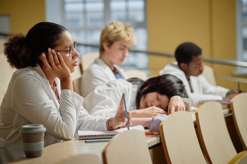 NPD-BC Certification Exam Preparation Medical student resting on desk in a lecture hall during a university class